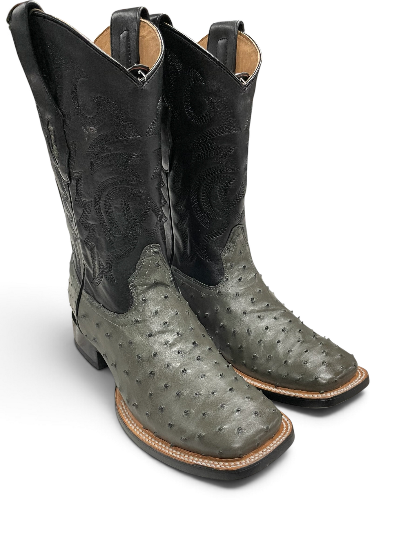 Botas vaqueras Botas El Pistolero PYP de avestruz gris con caño negro bordado y punta cuadrada sobre mesa de mármol.