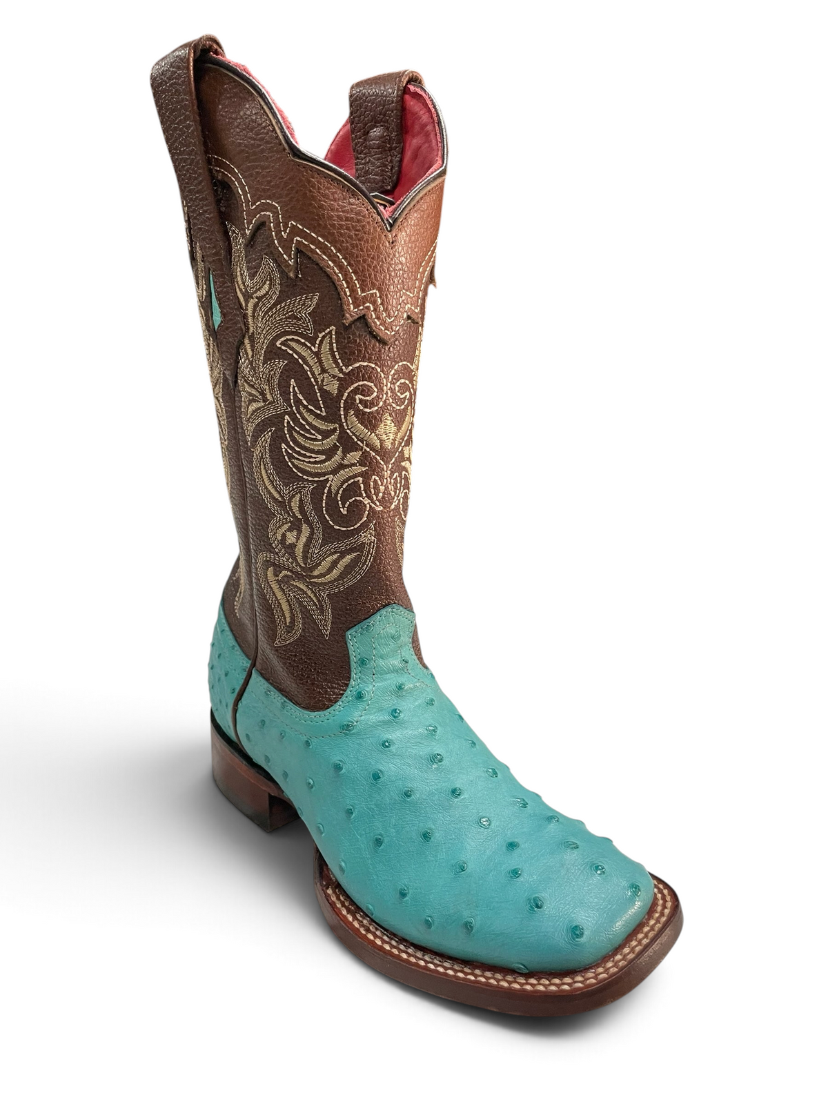 Botas El Pistolero PYP de piel de avestruz turquesa con caña café y bordados florales, estilo vaquero de punta cuadrada.