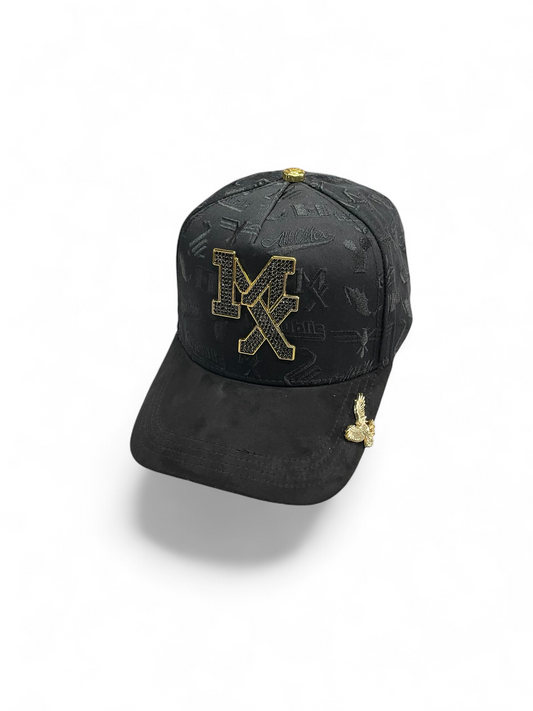 Gorra Botas El Pistolero PYP negra con emblema MX dorado brillante, textura grabada y detalle de águila en visera.