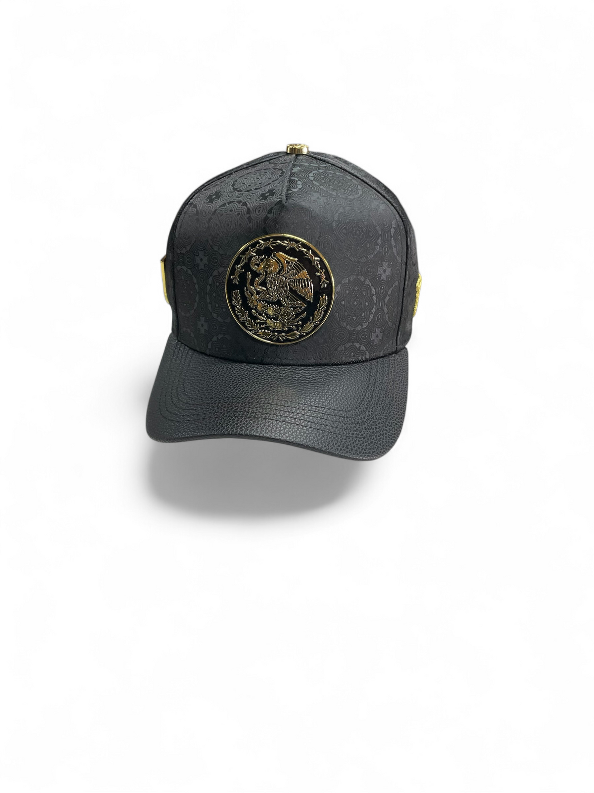 Gorra Botas El Pistolero PYP negra con patrón grabado, visera de textura piel y emblema metálico del escudo nacional.