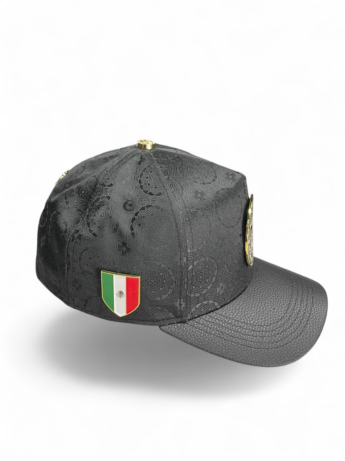 Gorra Botas El Pistolero PYP negra con patrón grabado, visera de piel sintética y emblema de la bandera de México.
