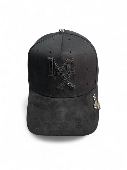 Gorra Botas El Pistolero PYP negra con monograma de pedrería, ala de terciopelo y detalle metálico de águila lateral.